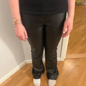Svarta skinnbyxor - Snygga svarta skinnbyxor med en tight passform. Byxorna har en hög midja och en stilren design som passar perfekt för en trendig look. Perfekta för att ge din outfit en edgy touch.