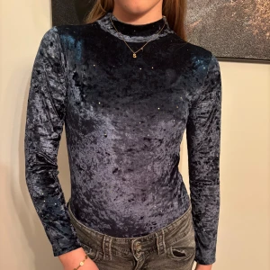 Grön body - Snygg grön body med långa ärmar och glittriga detaljer. Perfekt för en kväll ute eller en speciell tillställning. Toppen har en elegant passform och känns lyxig mot huden. 