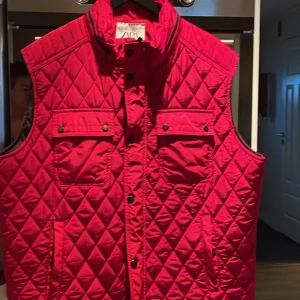 Röd quiltad väst från Zara - Säljer en snygg röd quiltad väst från Zara. Västen har en hög krage och knappar framtill. Str xxl. Använd endast ett par gånger så i jättefint skick.
