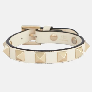 Vit läderarmband med nitar - Snyggt vitt läderarmband från Valentino med guldiga pyramidformade nitar. Perfekt accessoar för att ge en edgy touch till din outfit. Justerbart spänne för bästa passform. 