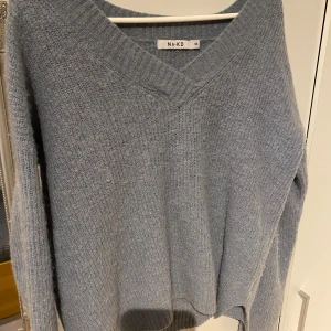 Ljusblå stickad tröja från NA-KD - Mysig ljusblå stickad tröja från NA-KD med v-ringning. Perfekt för kyliga dagar med sin mjuka och bekväma passform. Tröjan har långa ärmar och ribbade kanter för extra stil och komfort.