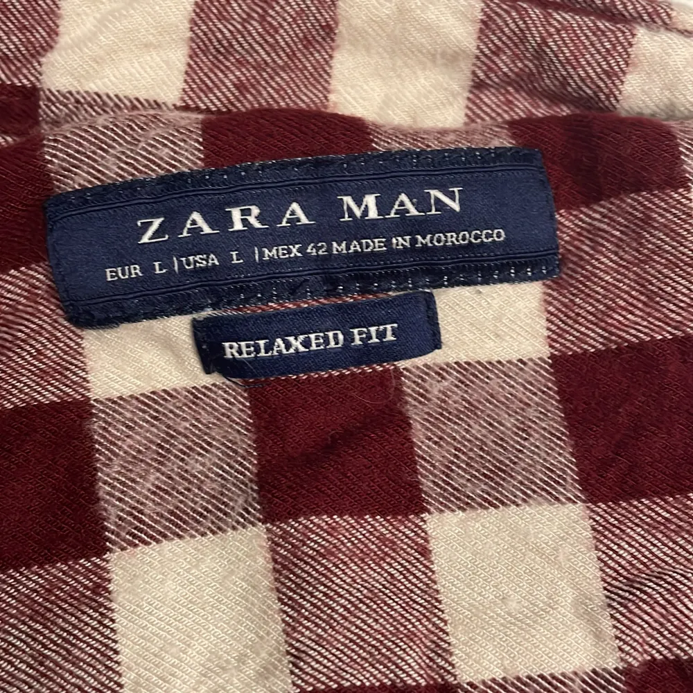 Säljer en rutig skjorta från Zara Man i avslappnad passform. Skjortan har ett klassiskt rutmönster i vinrött och vitt, med långa ärmar och knappar framtill. Perfekt för en stilren och bekväm look.. Paidat.
