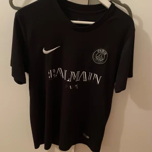 Svart PSG x Balmain fotbollströja - Den här tröjan är väldigt fin och skön och träna i, säljer pga den kommer inte till användning. Den har börjat tappa texten på bröstet men inget som förstör själva tröjan i sig. Säljer den billigt