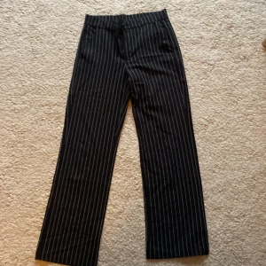 Svarta randiga byxor från Kappahl  - Snygga svarta byxor med vita ränder från Kappahl. De har en klassisk rak passform och är perfekta för en stilren look. Byxorna har en bekväm midja och är tillverkade i ett mjukt material. Byxorna är i storlek 152💕