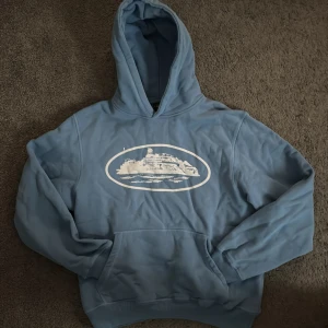 Blå corteiz hoodie  - Säljer en blå hoodie corteiz hoodie. Tröjan har en klassisk design med huva och en stor ficka framtill. Perfekt för en avslappnad stil.