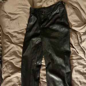 Svarta skinnbyxor från Bik Bok - Snygga svarta skinnbyxor från Bik Bok i storlek 36. Byxorna har en knapp och dragkedja framtill samt fickor både fram och bak. Perfekta för en trendig look.
