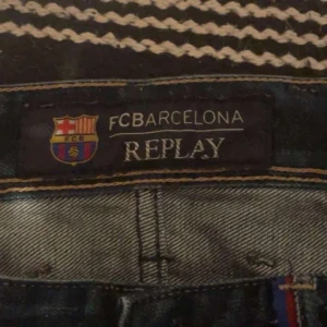 Anbass Replay jeans med Fc barcelona colab  - Snygga blå jeans från Replay med FC Barcelona-märke. Klassisk femficksdesign med knappgylf och broderad detalj på bakfickan. Perfekta för den som älskar både stil och fotboll.
