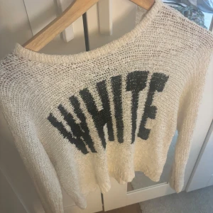Vit stickad tröja med text - Säljer en vit stickad tröja med svart text 'WHITE' på framsidan. Tröjan har en avslappnad passform och långa ärmar, perfekt för kyligare dagar. Den är både stilren och bekväm.