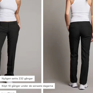 Svarta kostymbyxor - Snygga svarta kostymbyxor med låg midja och rak passform. Perfekta för en stilren look. Byxorna har en klassisk design med knappar och dragkedja framtill.