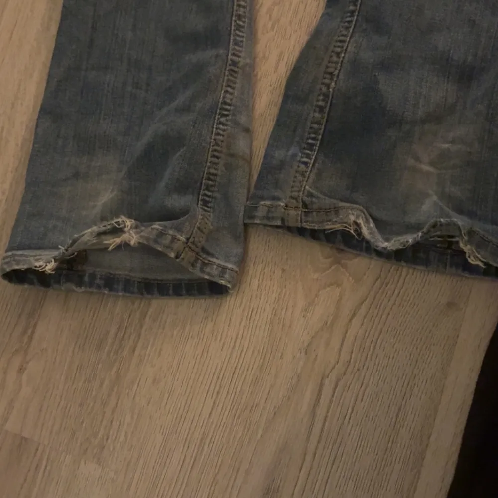 Snygga blå jeans från NLY Trend som inte säljs längre med slitna detaljer på knäna och bakfickan. De har en klassisk femficksdesign och knappgylf. Perfekta för en avslappnad stil. Är lite trampade på där nere, dock inget man täcker på!. Farkut & Housut.