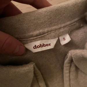 Beige tröja från Dobber - Säljer en stilren beige tröja från Dobber i storlek S. Tröjan har en klassisk krage och dragkedja framtill. Perfekt för en avslappnad och snygg look. Pris kan diskuteras.