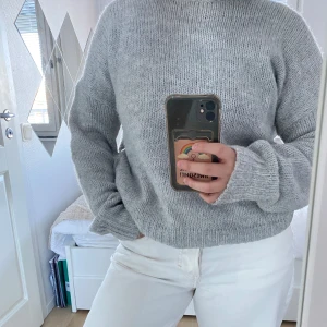 Grå stickad tröja från H&M - Mysig grå stickad tröja från H&M i storlek XS/S. Perfekt för kyliga dagar med sin mjuka och bekväma passform. Tröjan har långa ärmar och en klassisk rund halsringning.
