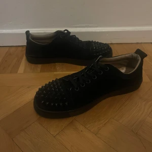 Christian Louboutin skor - Snygga svarta sneakers från Christian Louboutin med nitar på tån och snörning. Perfekta för att ge en edgy touch till din stil. Har bara varit använda ett par gånger