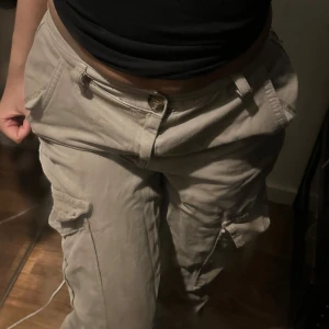 Low waist Beige cargobyxor - Snygga low waist beige cargobyxor med flera fickor och en avslappnad passform. Har bara använt max 2 gånger. Perfekta för en casual look. Byxorna har en dragkedja och knapp framtill. Går ner i pris skriv om ni har frågor. 💞
