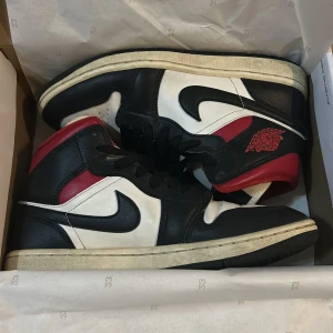 Nike Air Jordans i svart, vitt och rött - Säljer ett par klassiska Nike Air Jordans i svart, vitt och rött. Dom är välanvända och har inga större defter förutom veck framme på skorna som man ser på bild 4. Säljer p.g.a att jag inte använder dom längre. Skorna är i storlek 39. Orginal lådan följer med!🤗💕