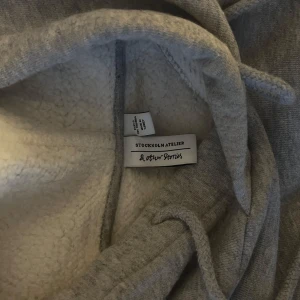 Grå hoodie från & Other Stories - Mysig grå hoodie från & Other Stories med en stor ficka framtill och justerbar huva. Perfekt för kyliga dagar med sin mjuka insida. köpt för 90€