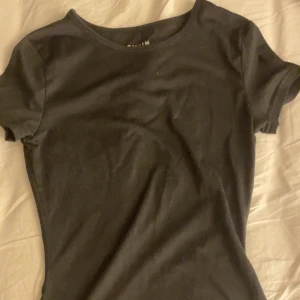 Svart t-shirt - En enkel och stilren svart t-shirt med rund halsringning och korta ärmar. Perfekt basplagg för alla tillfällen.