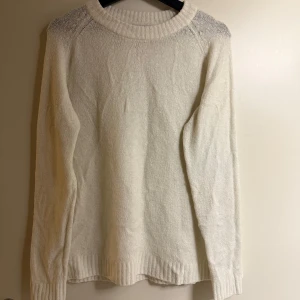 Vit stickad tröja från 157 - Säljer en stilren vit stickad tröja från 157. Tröjan har en klassisk design med långa ärmar och ribbstickade kanter vid hals, ärmslut och nederkant. Perfekt för kyliga dagar!