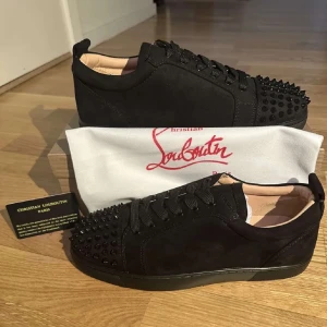 Christian Louboutin - Snygga svarta sneakers från Christian Louboutin med nitar på tån och snörning. Tillverkade i mocka för en lyxig känsla. Perfekta för att ge din outfit en edgy touch.