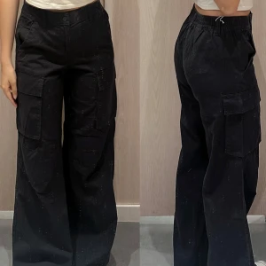Svarta cargopants med vida ben - Snygga svarta cargopants med vida ben och praktiska fickor på sidorna. Perfekta för en avslappnad och trendig look. Elastisk midja för extra komfort.