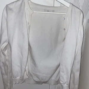 Vit kofta med knappar - Säljer en stilren vit kofta som jag inte vet vart den kommer i från, i storlek S. Koftan har långa ärmar och knappar framtill, perfekt för lager-på-lager-stil. Den är mjuk och bekväm, idealisk för både vardag och mer uppklädda tillfällen.