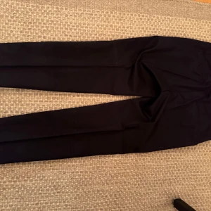 Mörkblå kostymbyxor från Esprit - Snygga mörkblå kostymbyxor från Esprit med dragkedja och knappstängning. Styva med lite stretch i. Passar i alla lägen, festen, båten, jobbet. Perfekta för en stilren look.