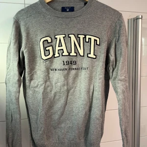 Stickad tröja från GANT - Säljer en stilren grå stickad tröja från GANT. Tröjan har långa ärmar och en rund halsringning. Perfekt för en avslappnad och snygg look. Använd sparsamt. Storlek XS