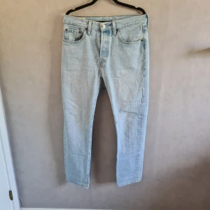 Ljusblå Levi's 501 jeans - Säljer ett par klassiska ljusblå Levi's 501 jeans. De är i bra skick och har rak passform. Fint skick, lite använda! Storlek: W27 L30 men uppsydda så längden är kanske L28-29
