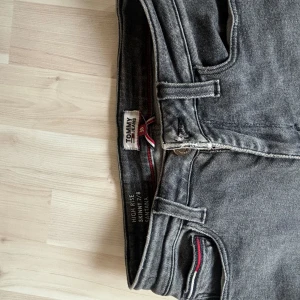 Tommy hilfiger Jeans  - Grå/svarta Jeans i high waist från Tommy Hilfiger med slitna slut på byxan.  Storleken är 26/30