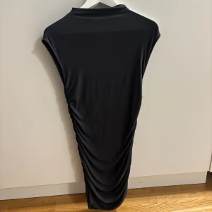 Svart klänning från Gina Tricot - Säljer en elegant svart klänning från Gina Tricot. Den har en stilren design med en åtsittande passform och ärmlös stil. Klänningen är i nyskick!