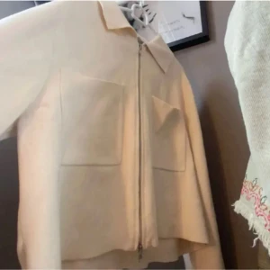 Sommar jacka Åhléns   - Säljer en snygg beige jacka från Alhens . Den har en dragkedja framtill och två stora fickor på bröstet. Perfekt för en stilren look!