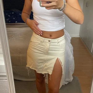 Beige/vit jeanskjol - Jeanskjol i storlek 34/XS. Liten reva vid benet men jag tycker att det är en snygg detalj