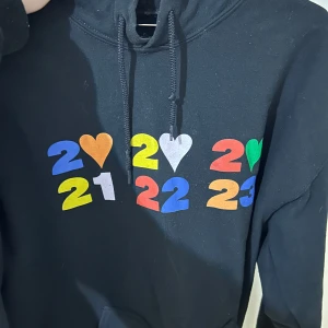Svart hoodie med färgglatt tryck - Svart hoodie från Harry styles merch, köpt i münchen 2023 under hans konsert. Storlek M/L men oversized. Använd ett antal gånger men inget fel på den:) Köpt för runt 900kr. 