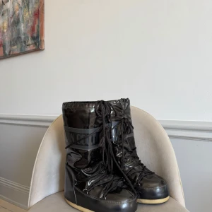 Svarta Moon Boots med snörning - Snygga unika Moon Boots med glansig yta och snörning framtill. Köpta för några år sedan men sparsamt använda! Storlek 35-38