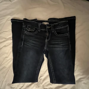 Mörkblå jeans från Gina Tricot - Snygga mörkblå jeans från Gina Tricot med kontrasterande vita sömmar. Klassisk femficksdesign och knappgylf. Perfekta för en avslappnad stil.