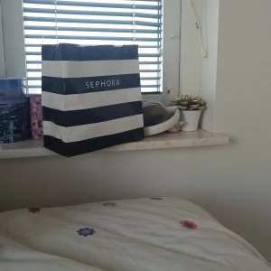 Sephora presentpåse - En stilren presentpåse från Sephora i svart och vitt randigt mönster. Perfekt för att ge bort skönhetsprodukter eller förvara dina egna sminkfavoriter.