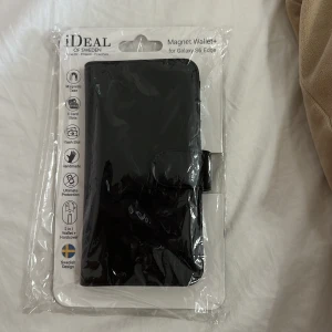 Svart magnetisk plånbok från iDeal of Sweden - Säljer en svart magnetisk plånbok för Galaxy S6 Edge från iDeal of Sweden. Den har plats för kort och fungerar även som ett skyddande fodral. Perfekt för att hålla allt samlat och säkert. Svensk design med stilren look.