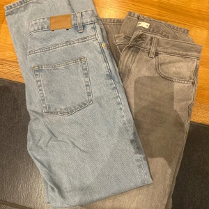 Blå och grå jeansbyxor - Snygga blå och grå jeansbyxor med klassisk femficksdesign och knappgylf. Perfekta för en avslappnad stil. Passar bra till både sneakers och kängor. Båda är i storlek 38 dom ljusa är från weekday och de grå är från Gina Tricot 