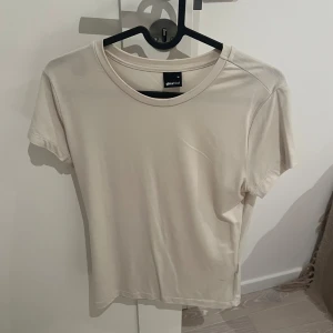 Beige tshirt GinaTricot - Säljer en stilren beige t-shirt från Gina Tricot. Använd fåtals gånger då den inte kom till användning.