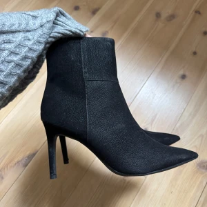 Svarta stövletter med klack från Next - Snygga svarta stövletter med spetsig tå och hög klack. Skorna har en dragkedja på sidan. Aldrig använda så nyskick!
