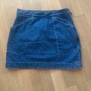Blå mini  jeanskjol Whyred - Snygg blå mini jeanskjol med dragkedja på sidan och praktiska fickor fram. Storlek 36 men liten så passar xs