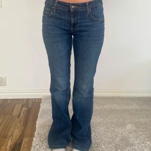 Blå jeans från Lee - Snygga blå lågmidjade jeans från Lee med bootcut-stil. De har en låg midja och klassisk femficksdesign. Perfekta för en avslappnad look.