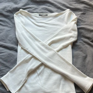 Vit långärmad topp från Gina Tricot - Säljer en stilren vit långärmad topp från Gina Tricot. Toppen har en enkel design med rund hals och är tillverkad i ett mjukt material som ger en skön passform. Perfekt för en minimalistisk look.