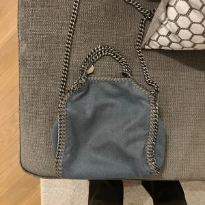 Stella McCartney väska mini - Snygg blå axelväska med kedjedetaljer längs kanterna och en lång kedjerem. Dustbag och kvitto finns. Köpare står för frakt eller hämta på Östermalm. Jättefint skick. ❤️ hör av er vid frågor!