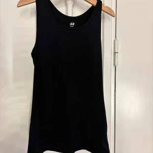 Svart linnetopp från H&M Sport - Säljer en svart linnetopp från H&M Sport. Perfekt för träning eller som ett basplagg. Toppen är ärmlös och har en klassisk rund halsringning. Materialet är mjukt och stretchigt för optimal komfort.