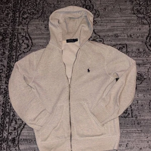 Ralph Lauren Zip  - Säljer en stilren Ralph lauren hoodie med en dragkedja. Skick 7/10 använt den några gånger, säljer därav den är för liten. Storlek S                                                                                       Hör av er vid frågor!                                    Små hål vid armen
