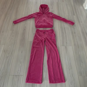 Rosa velour hoodie och byxor från Juicy Couture - Säljer en snygg rosa velour hoodie och matchande byxor från Juicy Couture. Storlek XS, 425kr för varje (totalt båda 1000kr) Hoodien har dragkedja och snörning i huvan, medan byxorna har resår och snörning i midjan. Perfekt för en avslappnad stil med en touch av lyx.