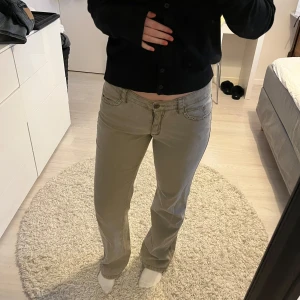 Lågmidjade jeans - Snygga beige/gröna byxor med nitar runt fickorna och broderade detaljer på bakfickorna. Byxorna har en lågmidjad passform och bootcut-stil. Storlek 38 men skulle säga att den passar 36 också.