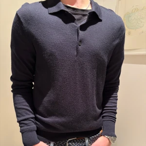 Svart långärmad pikétröja från Uniqlo - Säljer en stilren svart långärmad pikétröja från Uniqlo. Tröjan har en klassisk krage och knappar framtill, perfekt för en avslappnad men ändå uppklädd look. Passar till allt. Den är i merinoull Skriv om ni har frågor 