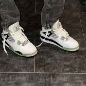 Nike Air Jordans i vitt och grönt - Snygga Nike Air Jordans i vitt med gröna och svarta detaljer. Skorna har en klassisk design med snörning och en bekväm passform. Perfekta för dig som vill ha en stilren look med en touch av färg.